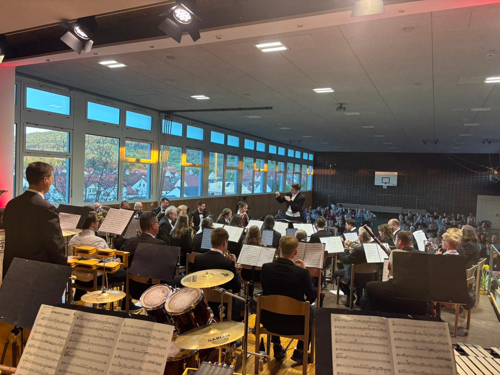 Blick über das Schlagwerk auf die Stammkapelle und den Dirigenten in der vollen Gemeindehalle