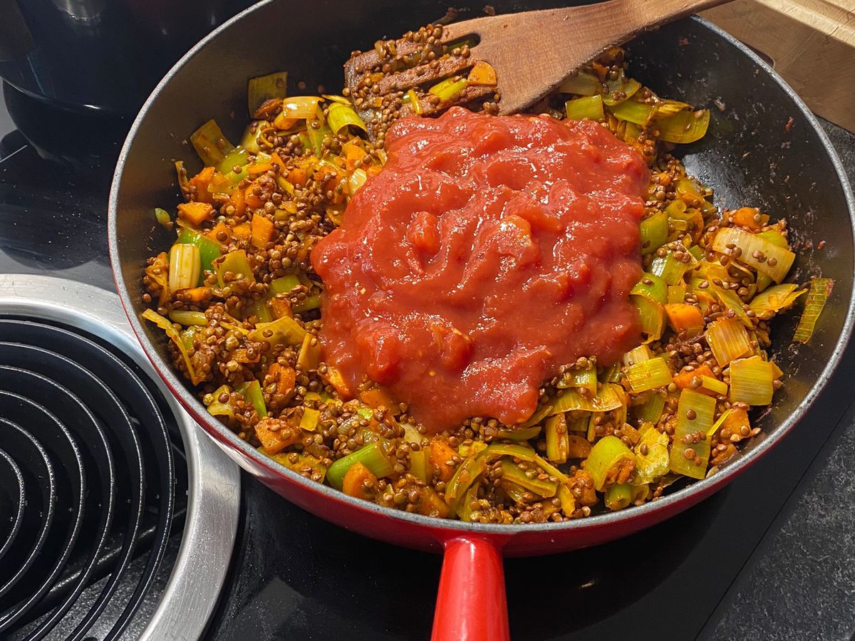 Linsen, Lauch und Karotten in der Pfanne, dazu passierte Tomaten