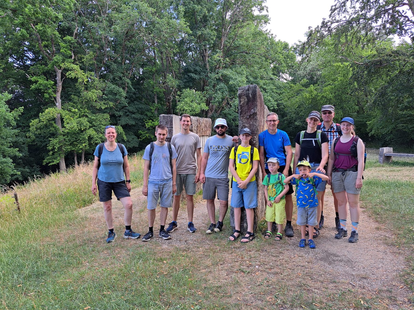 Die Wandergruppe mit Kindern auf einem Waldweg neben großen Steinplatten