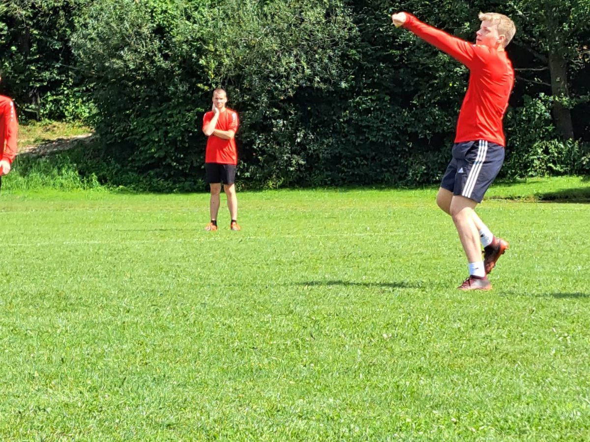 Ein Spieler schlägt, dahinter ein Mitspieler in Denkerpose