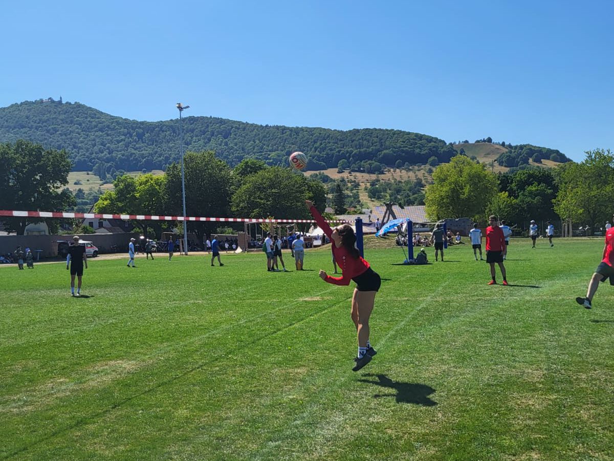Eine Spielerin springt zum Ball, dahinter die Burg Teck