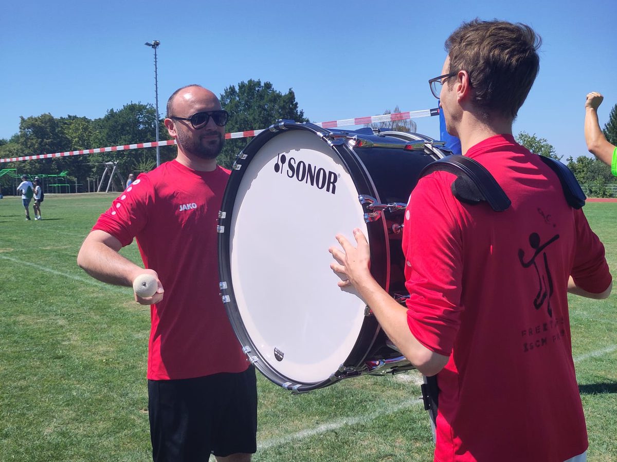 Zwei aus dem Team mit der umgehängten Trommel, auf dem Rücken der Teamname