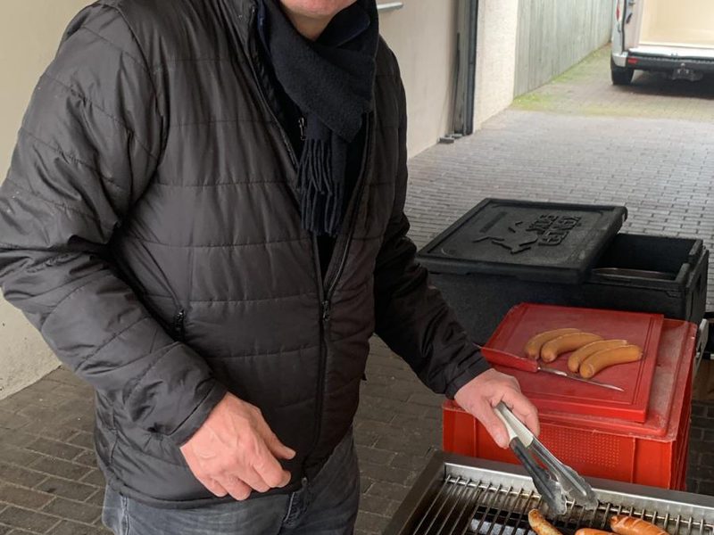 Ein Musiker in Winterjacke wendet lachend die Würste